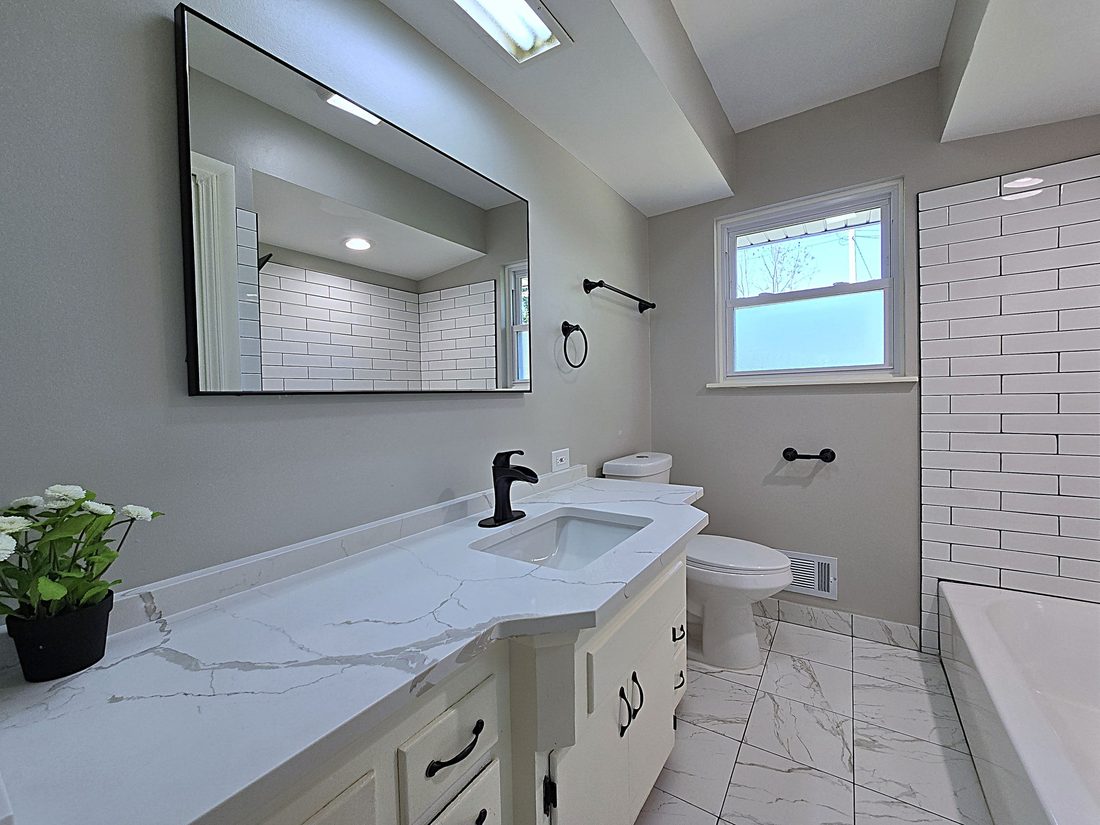 Remodeled full bathroom with quartz vanity and tile surround