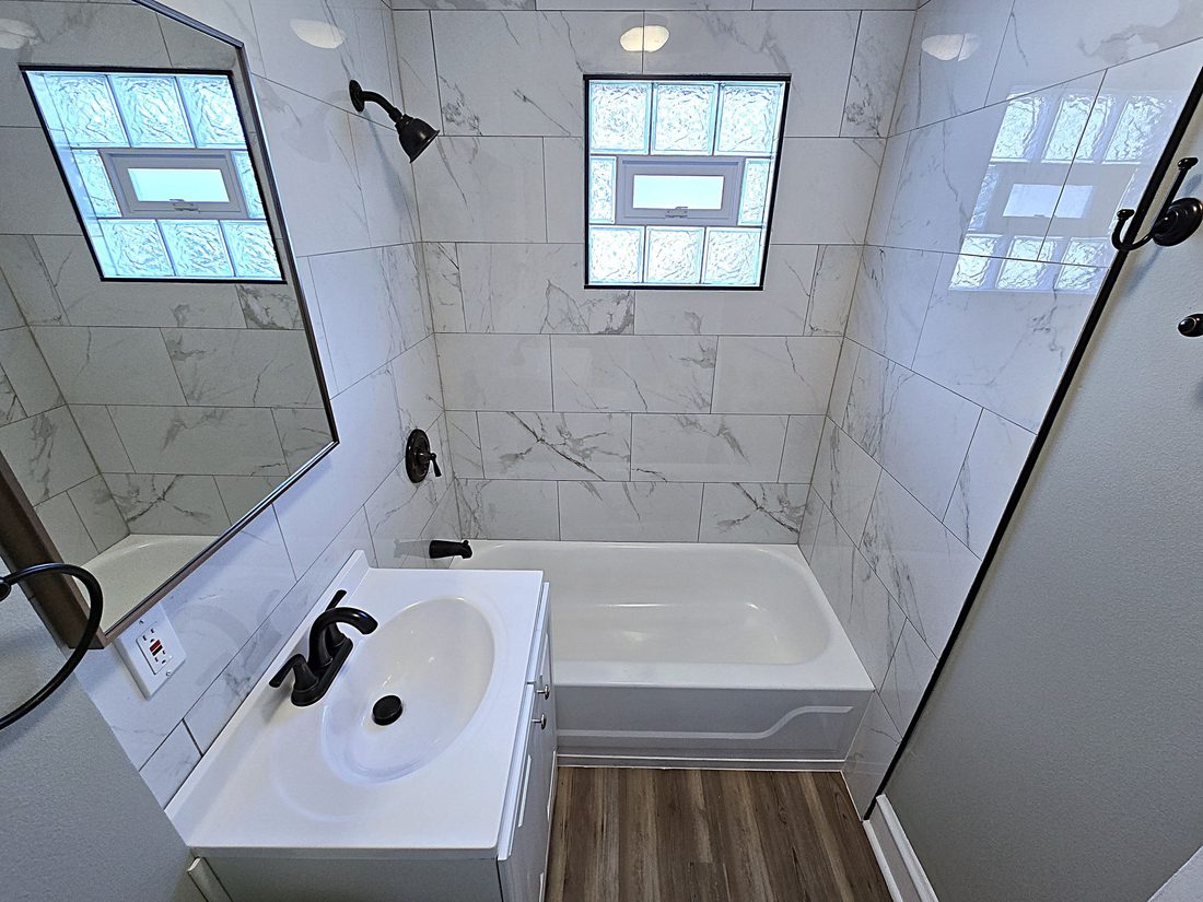 Renovated lower-level bathroom with a new tub, tile surround and glass panel