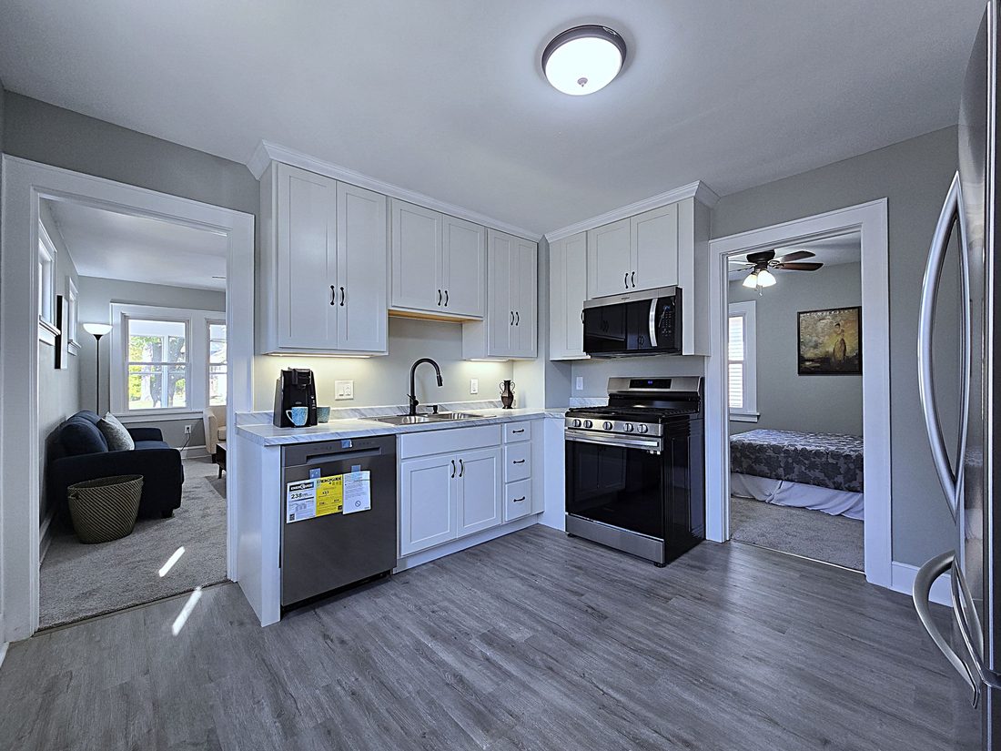 Renovated kitchen with white cabinetry, stainless appliances and new flooring