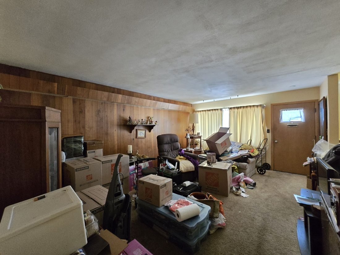 Milwaukee living room with wood panelling and stored belongings before the sale