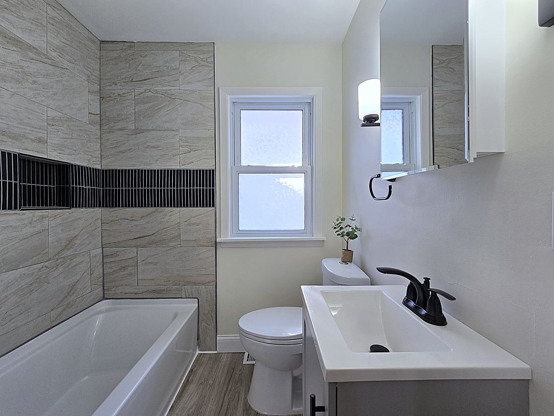 Updated bathroom with new vanity, tiled tub surround and black fixtures