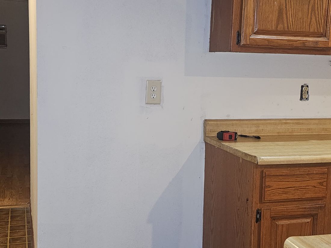 Kitchen corner with dated cabinets and tile flooring