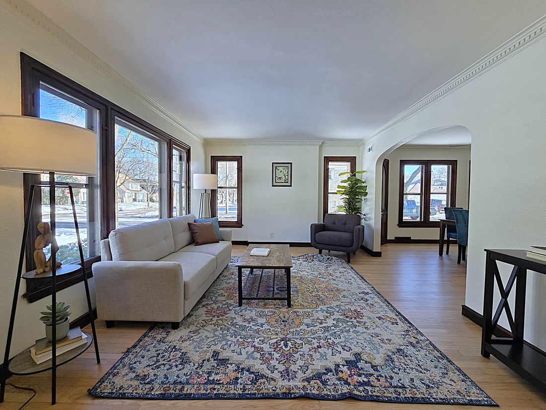 Staged living room with refinished hardwood floors and original wood-trimmed windows